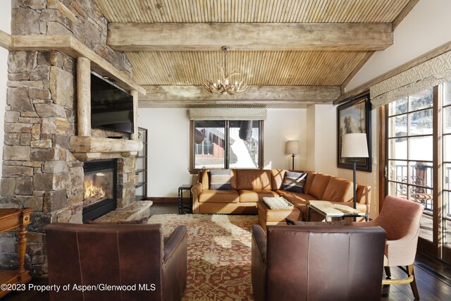 living room featuring a stone fireplace, plenty of natural light, wood ceiling, and an inviting chandelier