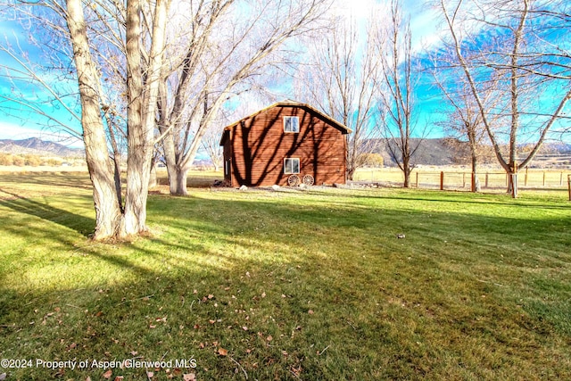 view of yard featuring a mountain view, a rural view, and an outdoor structure