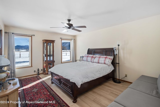 bedroom with ceiling fan, light hardwood / wood-style floors, and multiple windows