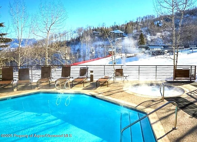 snow covered pool with a mountain view and a patio area