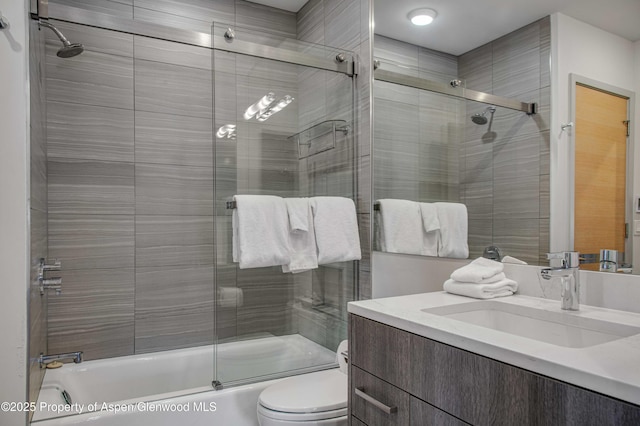 full bathroom featuring bath / shower combo with glass door, vanity, and toilet