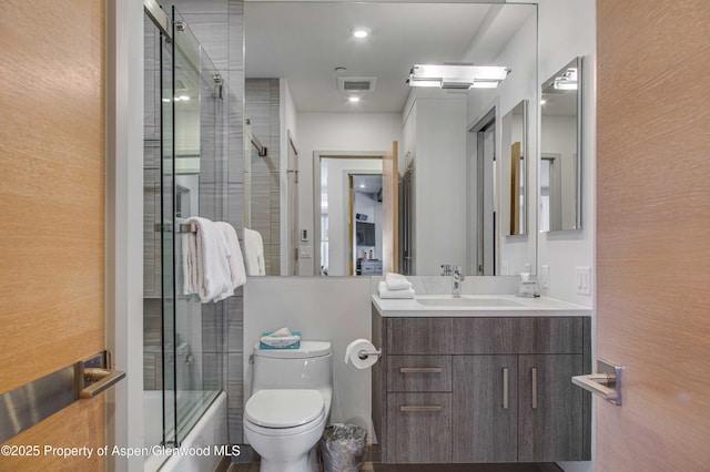 full bathroom with bath / shower combo with glass door, vanity, and toilet