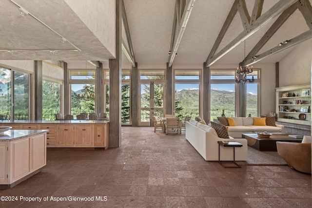 unfurnished sunroom with a mountain view, beam ceiling, plenty of natural light, and an inviting chandelier