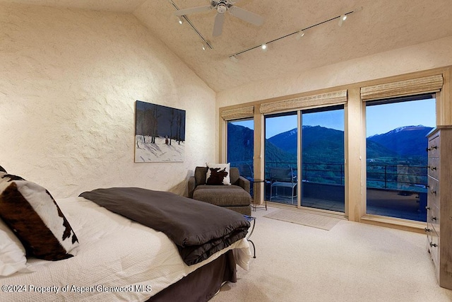 carpeted bedroom featuring access to exterior, ceiling fan, high vaulted ceiling, a mountain view, and track lighting