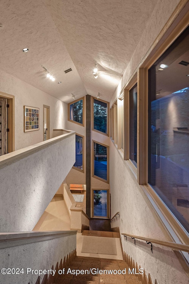 stairs featuring a textured ceiling and lofted ceiling