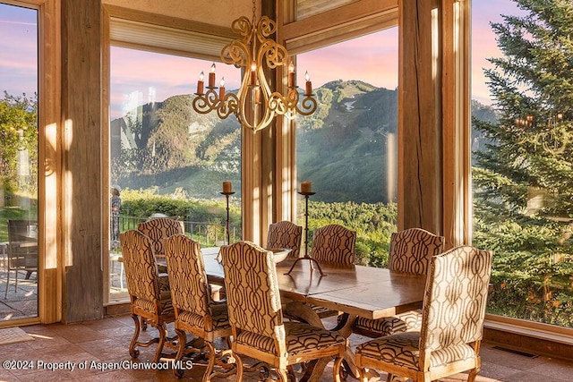 dining space with a mountain view, a healthy amount of sunlight, and an inviting chandelier