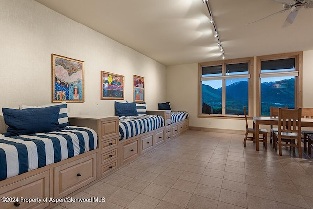 tiled bedroom with a mountain view, rail lighting, and ceiling fan