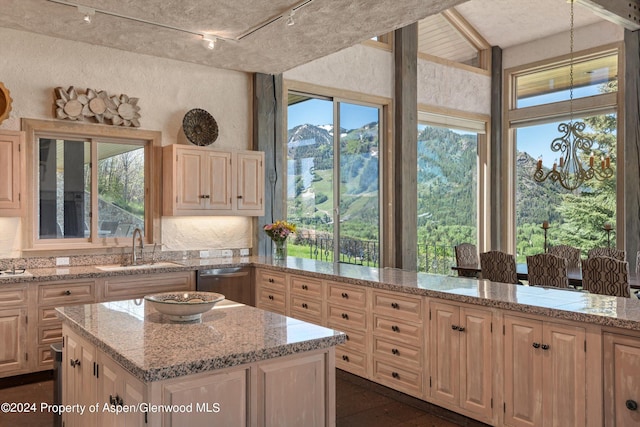 kitchen with stainless steel dishwasher, plenty of natural light, light stone countertops, and sink