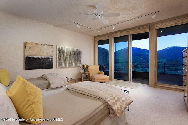 carpeted bedroom featuring a mountain view, ceiling fan, and access to exterior