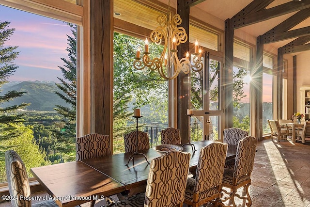 unfurnished sunroom with a mountain view, vaulted ceiling, a wealth of natural light, and a chandelier