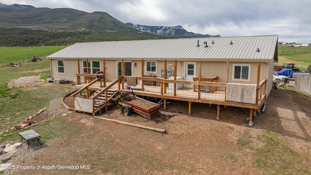 rear view of house featuring metal roof, a deck with mountain view, and fence