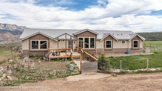 view of front of property with fence, a wooden deck, board and batten siding, and metal roof