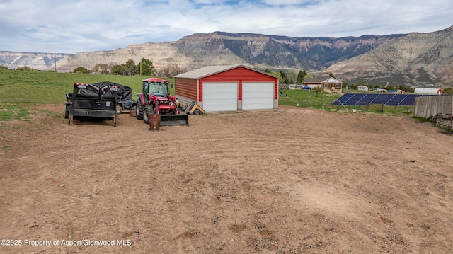 exterior space featuring a detached garage, a mountain view, and an outbuilding
