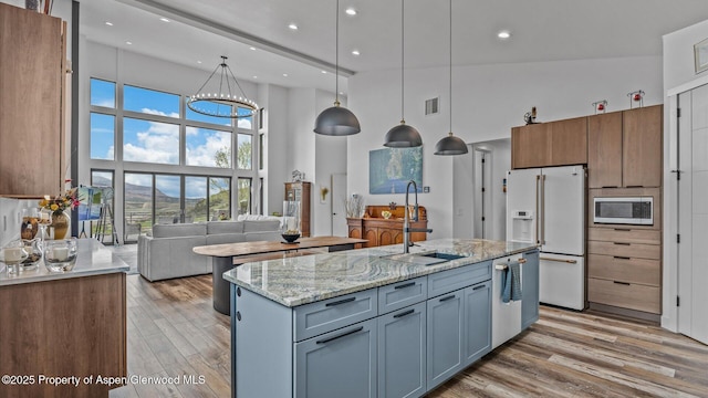 63 Meadow Creek Ct, Battlement Mesa, CO 81635 - kitchen featuring a towering ceiling, stainless steel appliances, a sink, light wood-style floors, and a kitchen island with sink