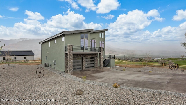 63 Meadow Creek Ct, Battlement Mesa, CO 81635 - view of side of home featuring a balcony, concrete driveway, an attached garage, a mountain view, and stucco siding