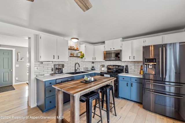 kitchen featuring white cabinetry, sink, tasteful backsplash, blue cabinets, and black appliances