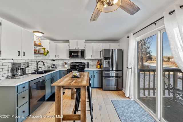 kitchen featuring backsplash, black appliances, white cabinets, sink, and light wood-type flooring