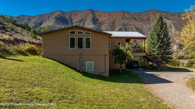 view of home's exterior featuring driveway, a yard, stairway, and stucco siding