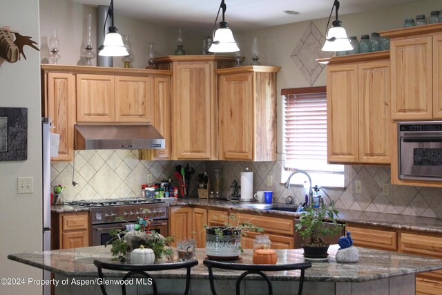 kitchen with pendant lighting, wall chimney range hood, a sink, and double oven range