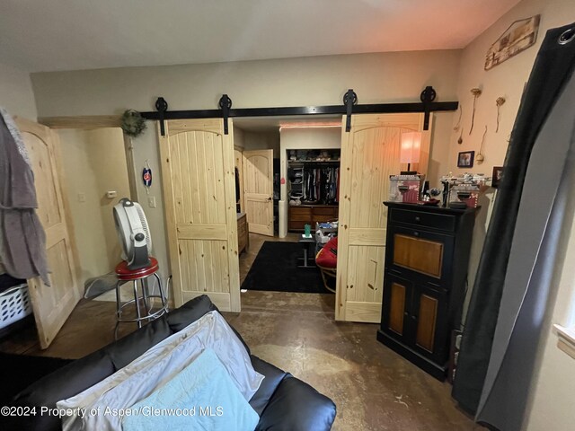 bedroom featuring a barn door, a closet, a walk in closet, and unfinished concrete floors