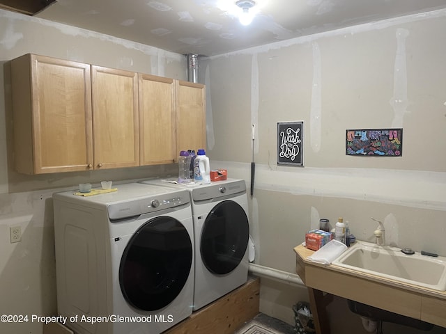 clothes washing area featuring washer and clothes dryer, a sink, and cabinet space