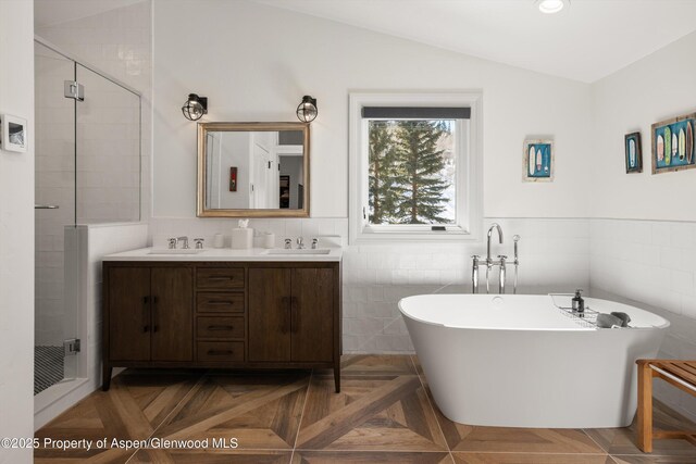 bathroom featuring double vanity, a freestanding bath, a stall shower, a sink, and vaulted ceiling