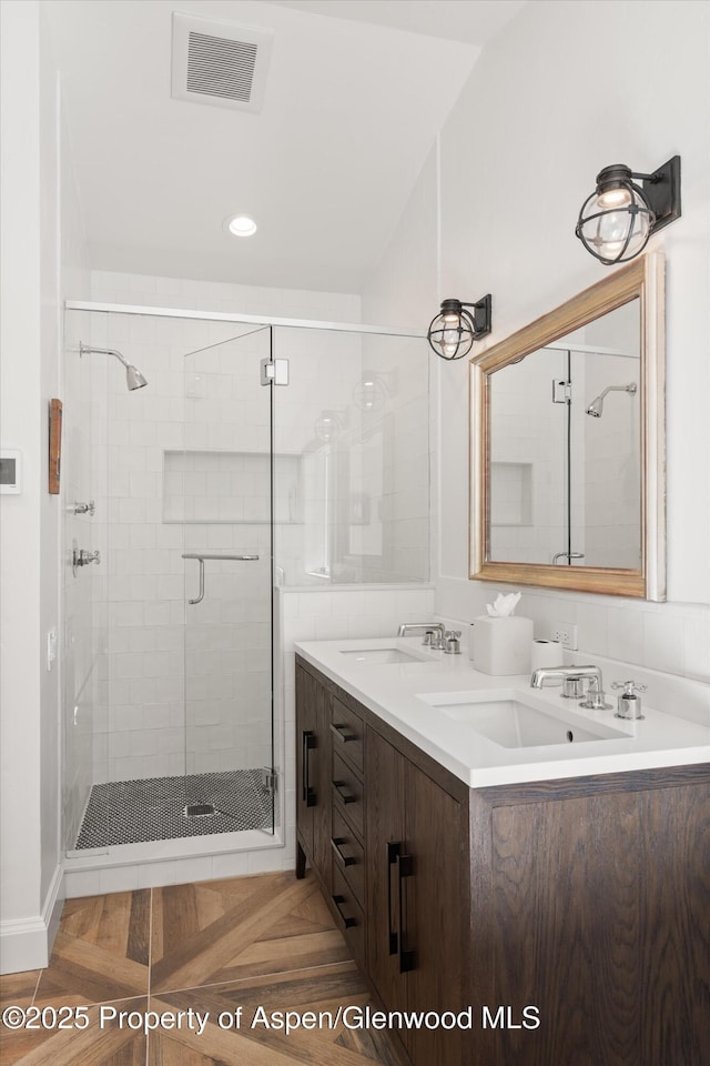 bathroom featuring a stall shower, visible vents, a sink, and double vanity