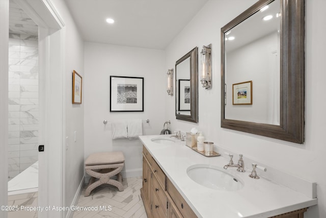 bathroom with recessed lighting, a sink, baseboards, a tile shower, and double vanity