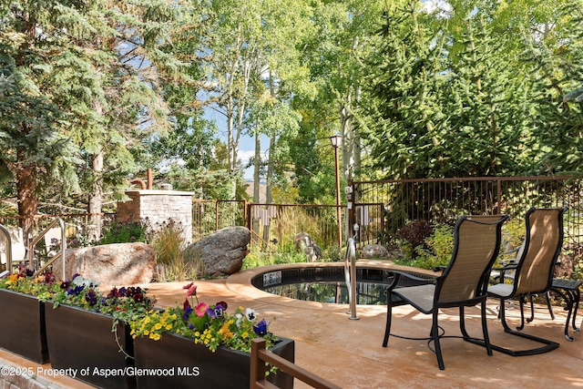 view of patio featuring fence and an in ground hot tub