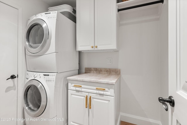 laundry room with cabinet space, baseboards, and stacked washer and dryer