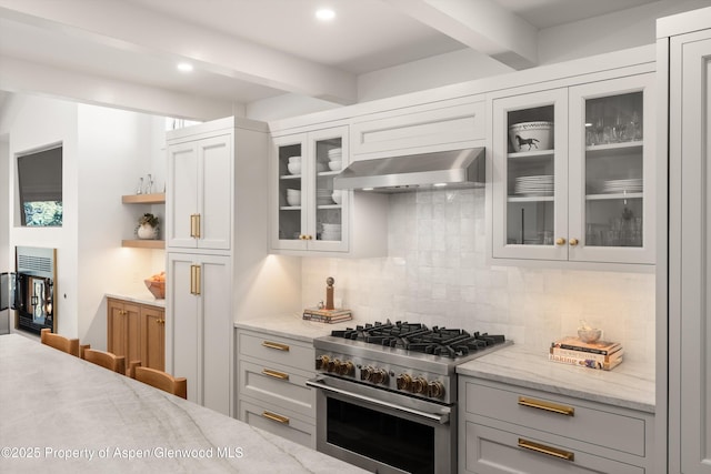 kitchen with beam ceiling, backsplash, glass insert cabinets, high end range, and extractor fan