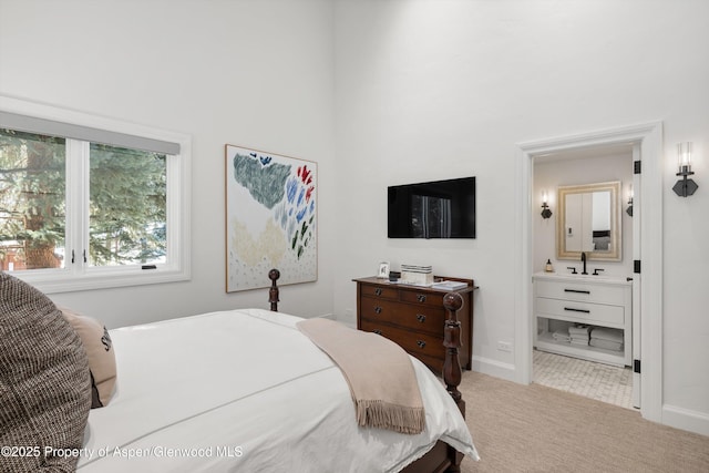 bedroom featuring carpet floors, a sink, baseboards, and ensuite bathroom