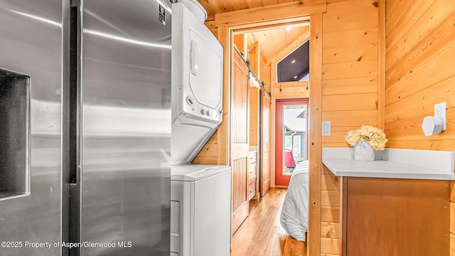 329 River Frontage Rd # 14, Silt, CO 81652 - washroom featuring stacked washer / drying machine, light wood-style floors, and wooden walls