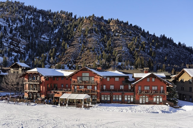 snow covered back of property with a mountain view