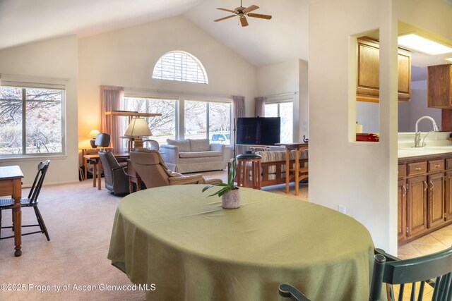 dining space featuring high vaulted ceiling, a ceiling fan, and light colored carpet