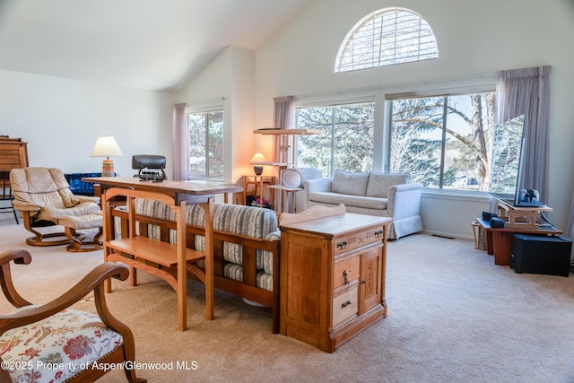 sitting room with high vaulted ceiling, a healthy amount of sunlight, visible vents, and light colored carpet