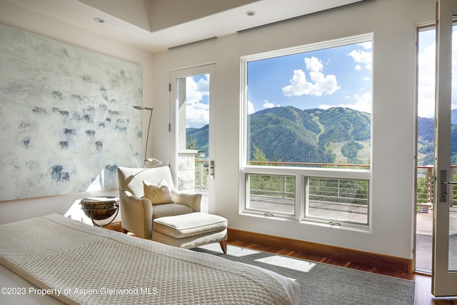 bedroom featuring a mountain view, access to exterior, dark hardwood / wood-style floors, and multiple windows