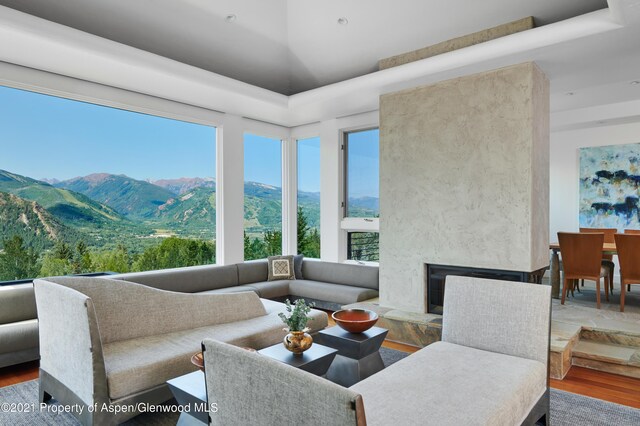 living room featuring a wealth of natural light, a mountain view, a premium fireplace, and wood-type flooring