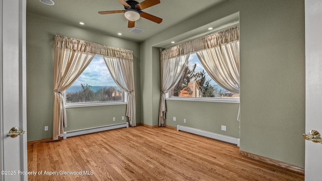 spare room featuring light wood-type flooring, ceiling fan, and a baseboard radiator