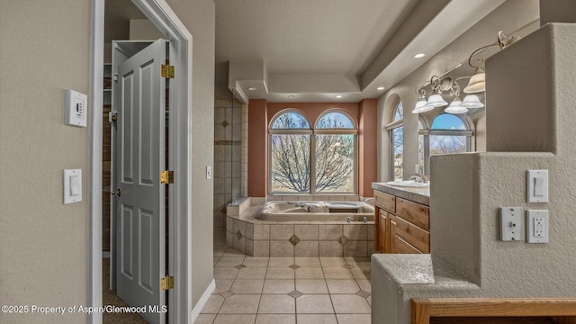 bathroom with tile patterned flooring, tiled tub, and vanity