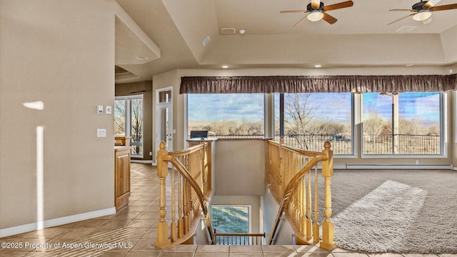 corridor featuring light tile patterned floors, a tray ceiling, and a baseboard radiator