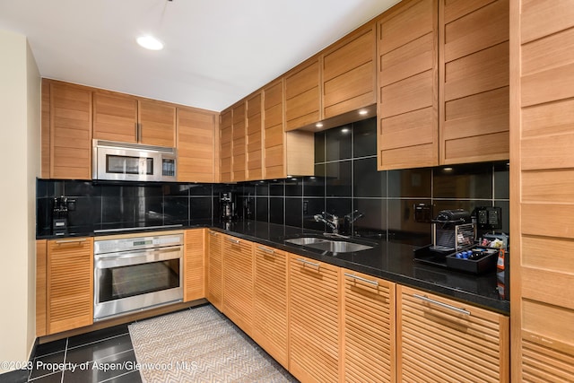 kitchen with decorative backsplash, dark stone counters, stainless steel appliances, sink, and light tile patterned floors