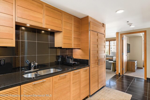 kitchen featuring dark tile patterned floors, sink, and dark stone counters