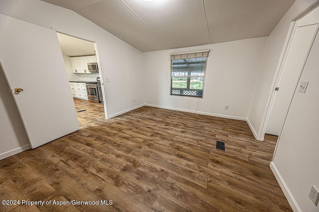 261 Ellis Ave, Maybell, CO 81640 - unfurnished bedroom with dark wood-style floors, visible vents, a textured ceiling, and lofted ceiling