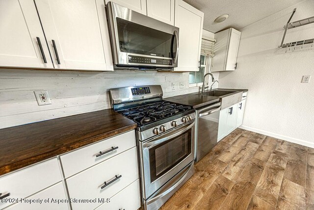 261 Ellis Ave, Maybell, CO 81640 - kitchen featuring appliances with stainless steel finishes, dark wood-style flooring, white cabinets, and a sink