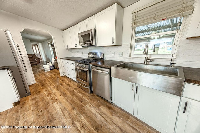 261 Ellis Ave, Maybell, CO 81640 - kitchen with appliances with stainless steel finishes, dark countertops, plenty of natural light, arched walkways, and wood finished floors