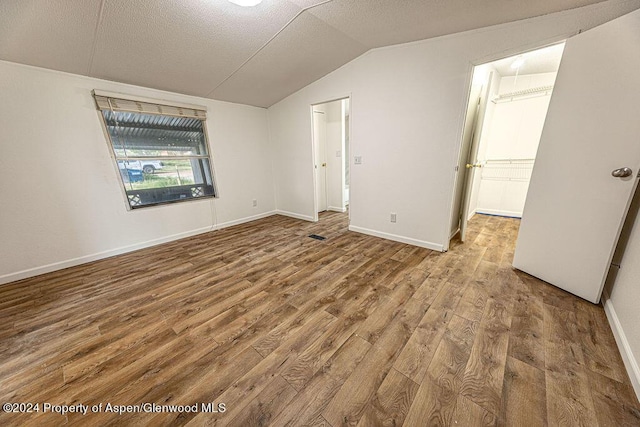 261 Ellis Ave, Maybell, CO 81640 - unfurnished bedroom with a textured ceiling, wood finished floors, vaulted ceiling, and baseboards