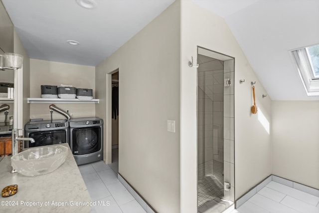 bathroom with washing machine and dryer, tile patterned flooring, an enclosed shower, and vaulted ceiling with skylight