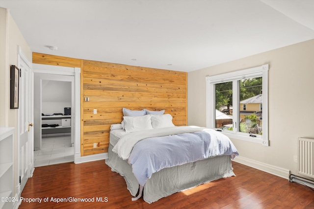 bedroom featuring radiator, wood walls, and dark wood-type flooring