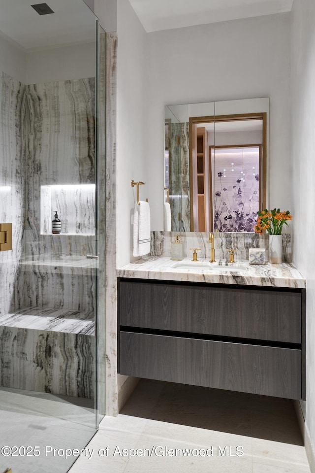 full bathroom featuring a marble finish shower and vanity